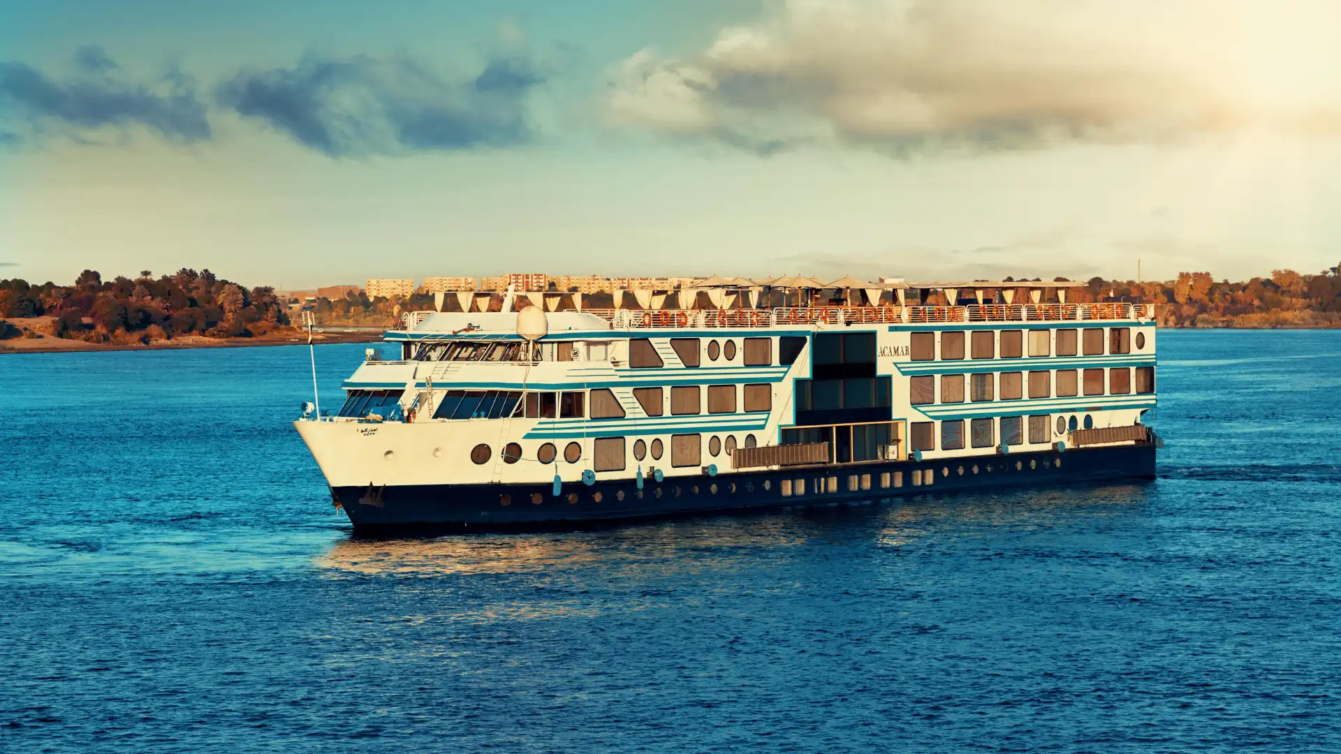Luxury five-star Nile cruise vessel sailing at golden hour past ancient temple